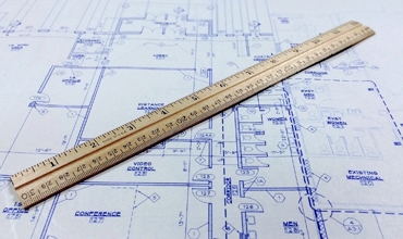 A ruler on a blueprint, measuring the dimensions of a building plan.