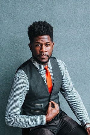 A man in a vest and tie sitting on a chair.