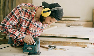A man operating a circular saw on a wooden table, creating precise cuts with focused concentration.